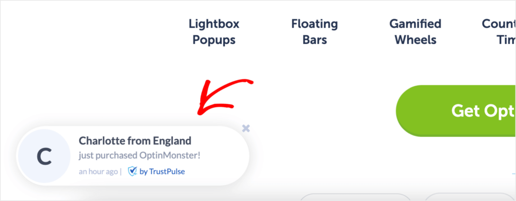 A TrustPulse notification on OptinMonster's website. It says "Charlotte from England just purchased OptinMonster!" Smaller, gray text says "an hour ago."